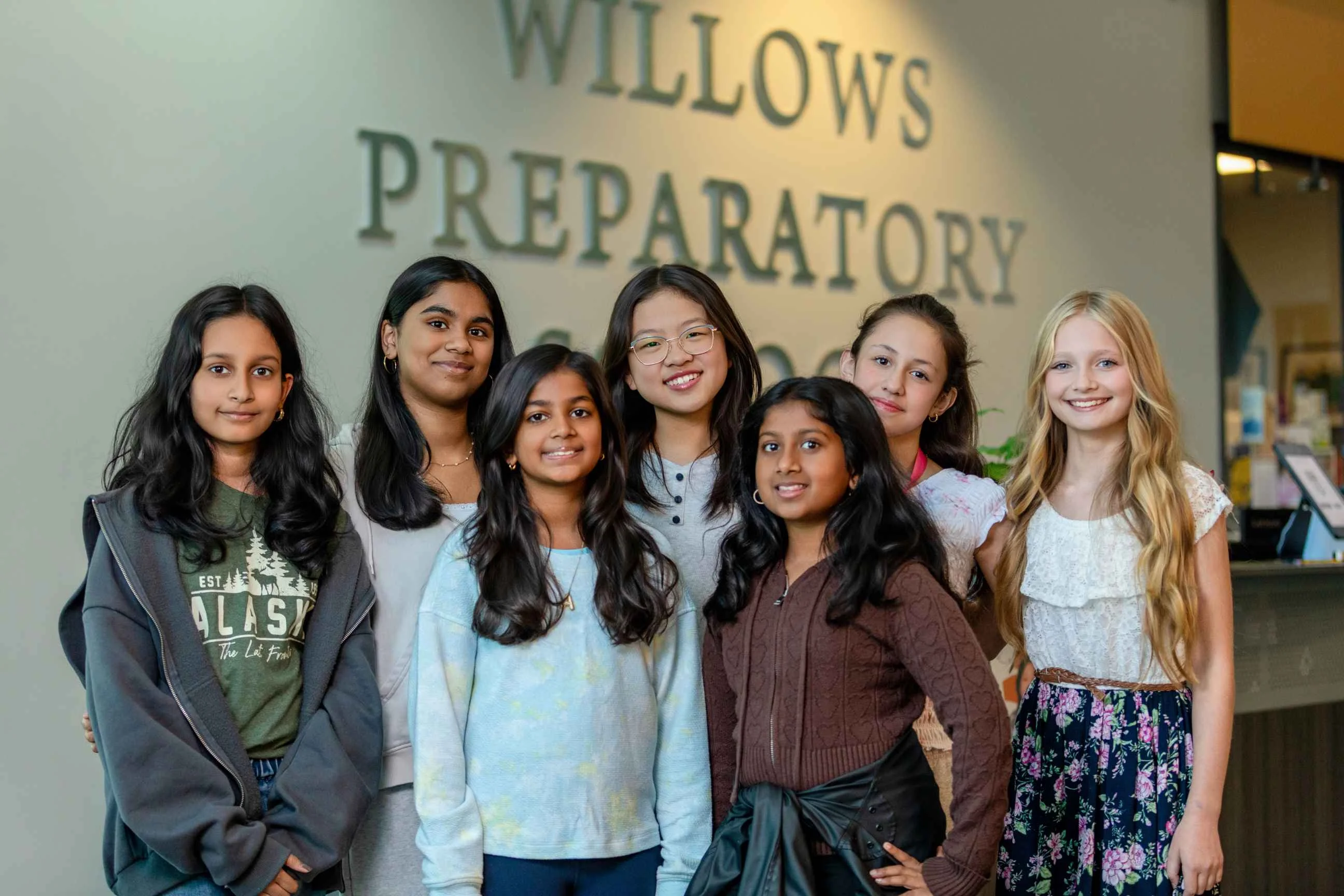 Diverse group of middle school girls smiling in front of Willows Preparatory School sign