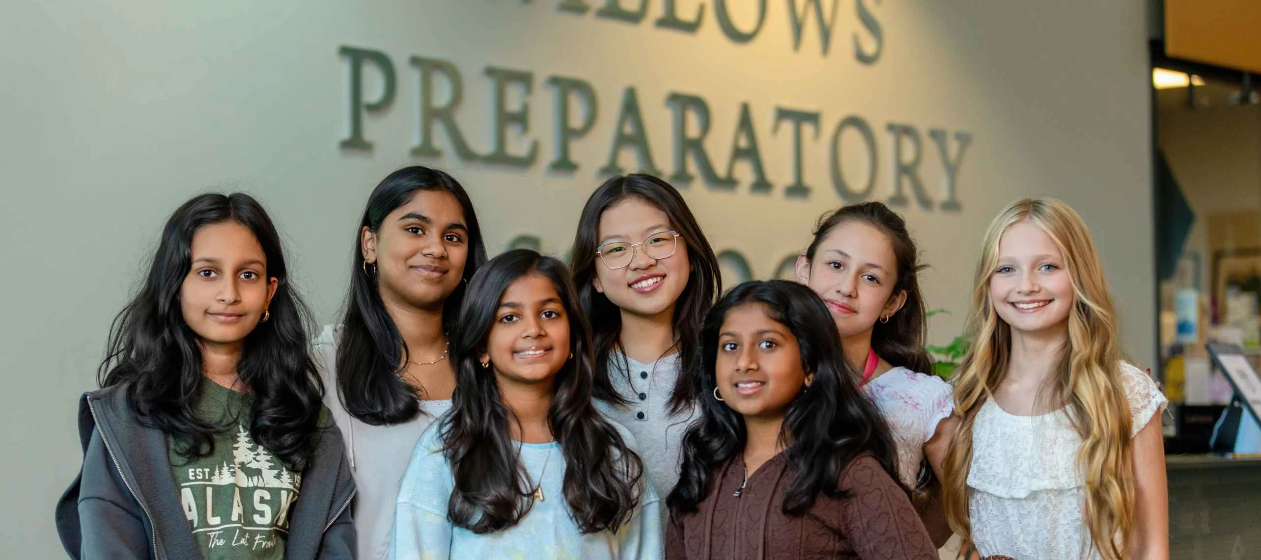 Diverse group of middle school girls smiling in front of Willows Preparatory School sign